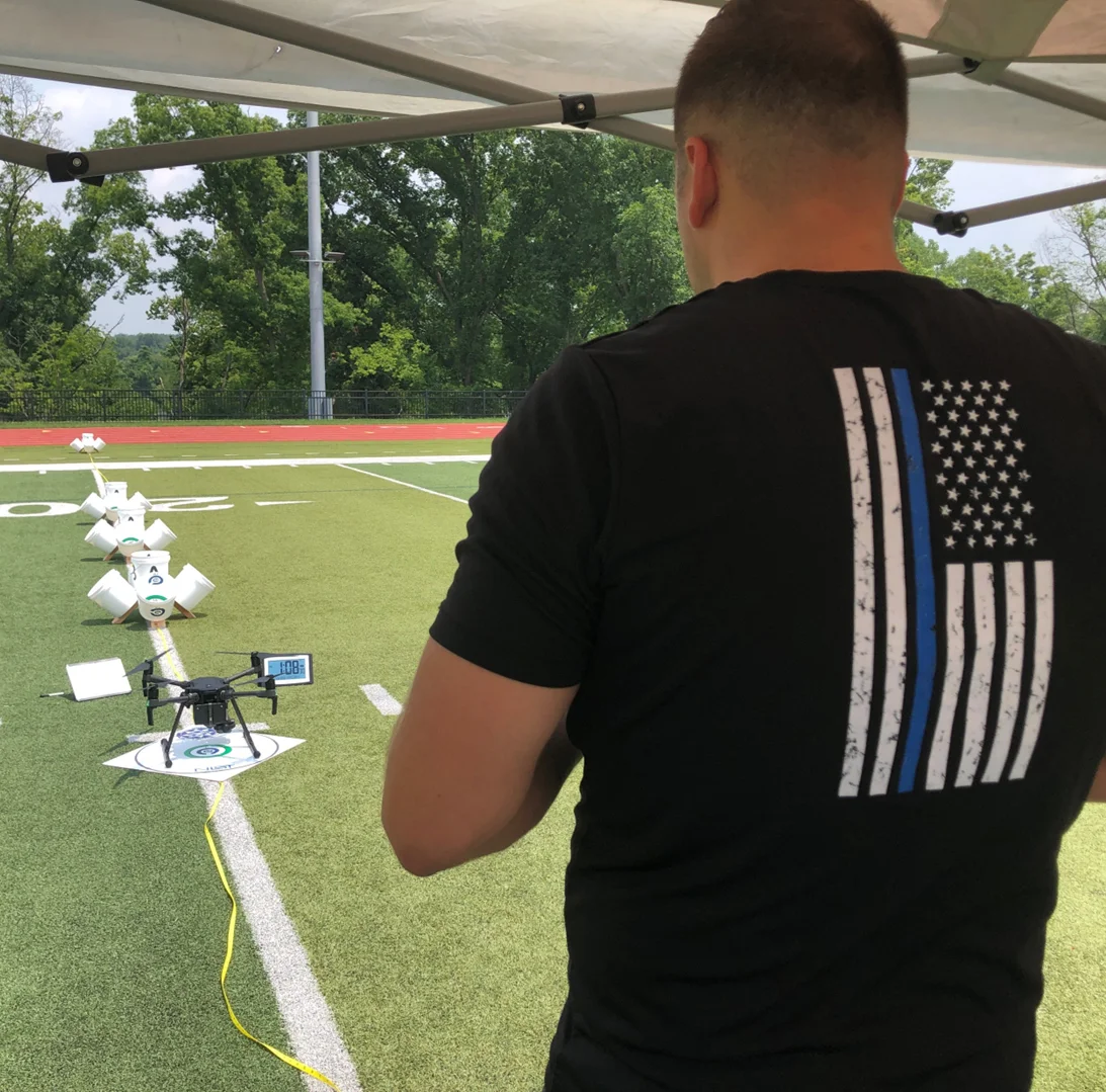 Drone operator preparing for a field test with a line of bucket targets